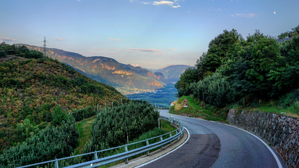 Kurvige Bergstraße mit grünen Bäumen und Bergen im Hintergrund
