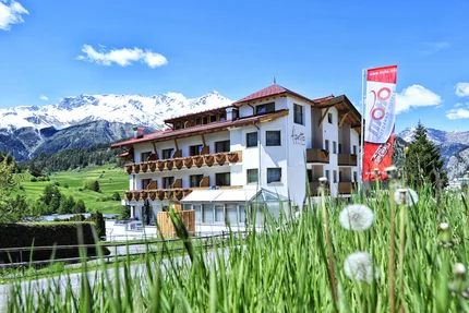 Hotel in den Alpen mit schneebedeckten Bergen und grünem Gras im Vordergrund
