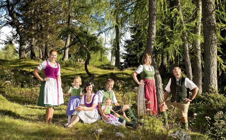 Family in traditional attire sitting and standing in a sunny forest