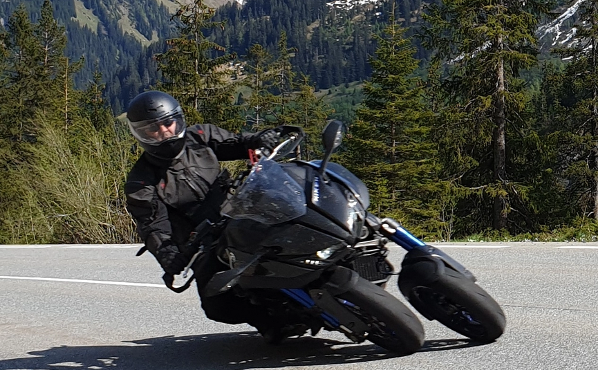Motorradfahrer fährt in den Bergen auf kurviger Straße