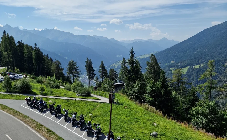 Motorcycles parked along a mountain road with alpine landscape view