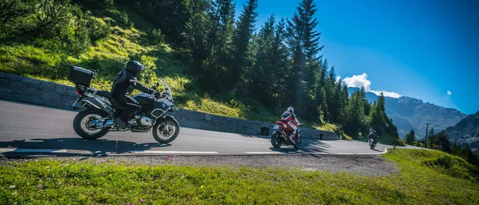 Motorcyclists riding on a winding mountain road in sunny weather