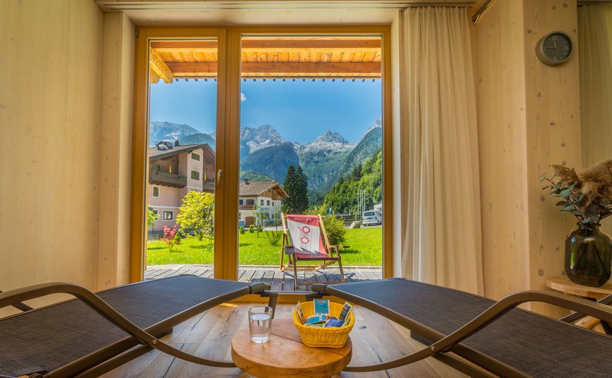 Liegestühle in Zimmer mit Bergblick durch große Fenster