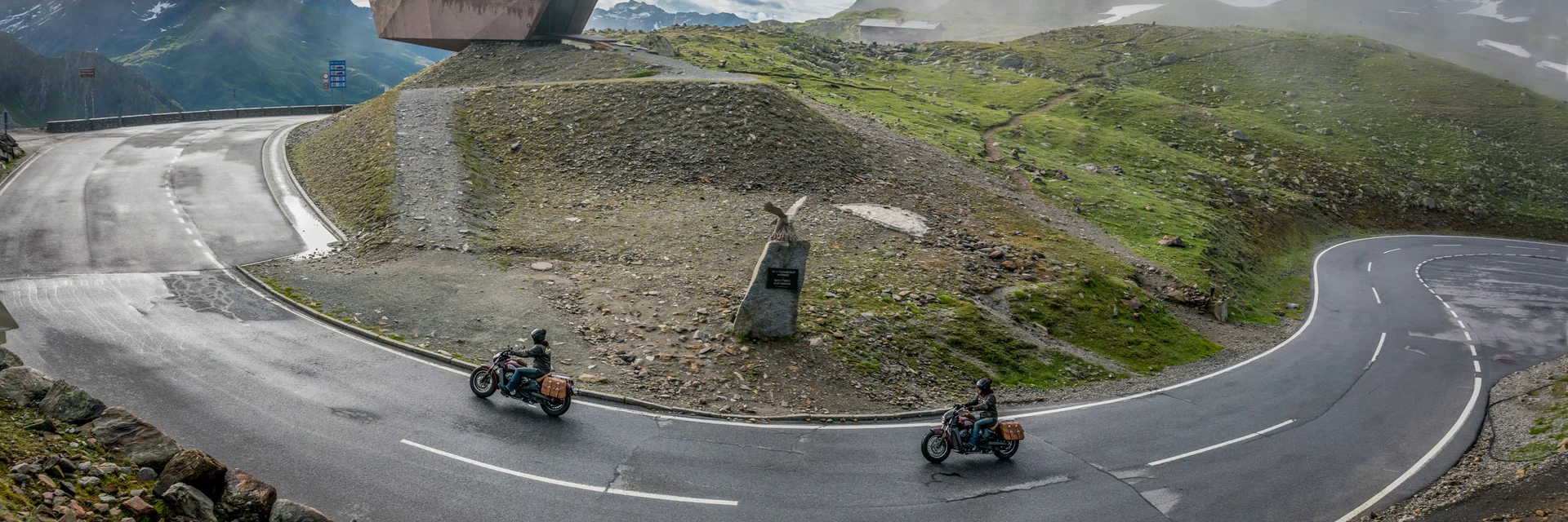 Winding mountain road with two motorcyclists and foggy viewpoint