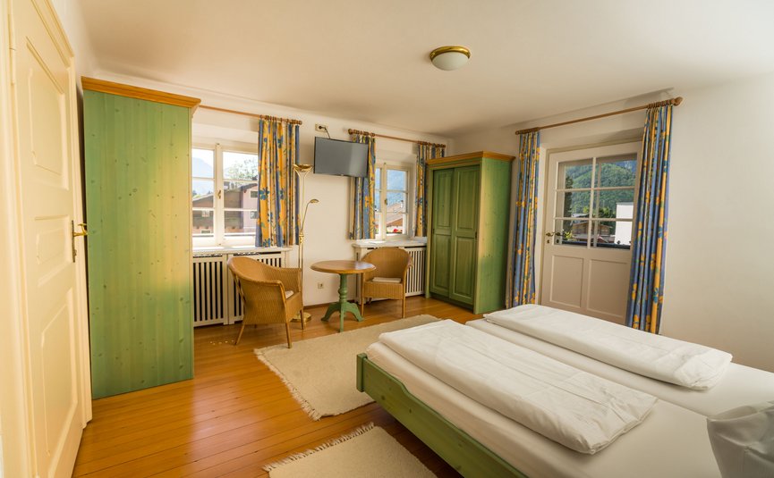 Gemütliches Schlafzimmer mit grünem Holzmobiliar und Bergblick