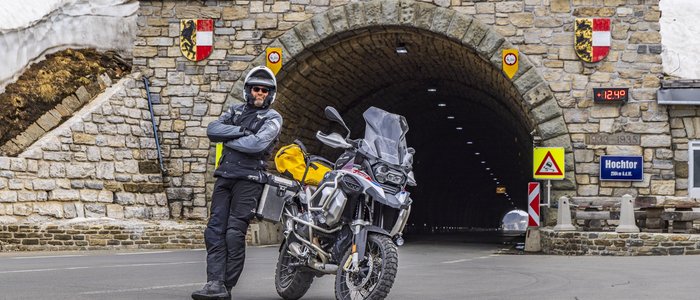 Erlebnishotel Kärnten-Mölltal ***S © Alexander Seger Motorradfahrer vor einem Tunnel mit Gedenktafel und Schneefeldern