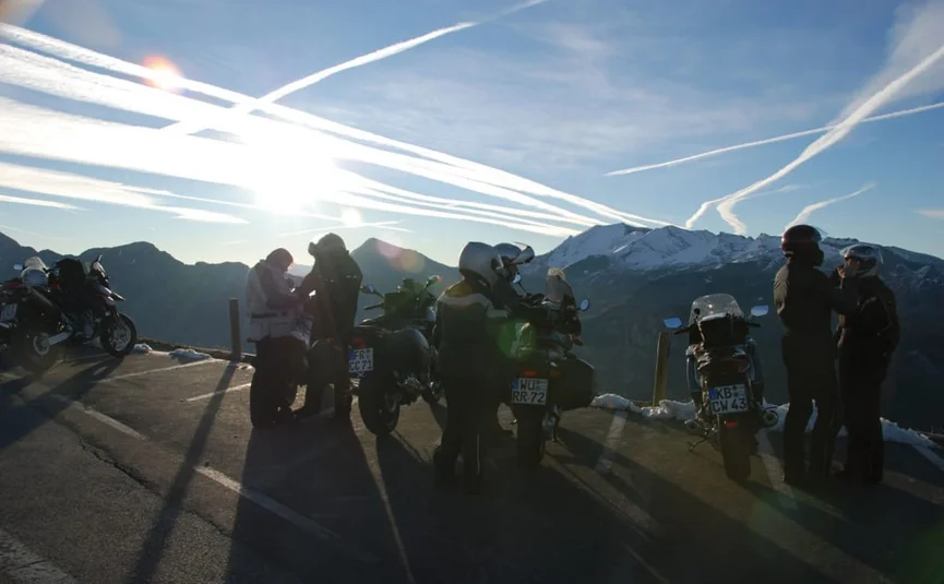 Motorrijders op bergweg met zonsondergang en bergen op de achtergrond