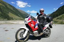 Motorcycle rider in protective gear on bike in mountainous area