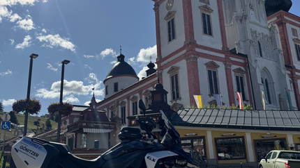 Kerzerl anzünden in Mariazell Motorrad vor historischer Kirche im Sonnenschein