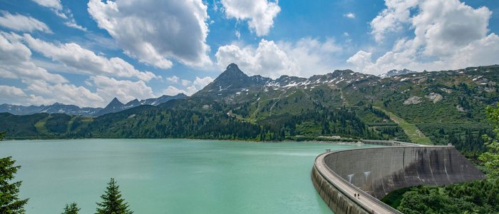 Paznaun – Silvretta © Golm Silvretta Luenersee Tourismus GmbH - Patrick Saely Stausee mit Bergkulisse und Staumauer unter blauem Himmel mit Wolken