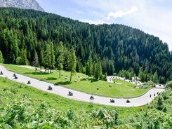 Valsugana – Kaiserjägerstraße – Val di Fiemme © Daniele Rodorigo Motorradfahrer fahren eine kurvige Bergstraße durch grüne Wälder