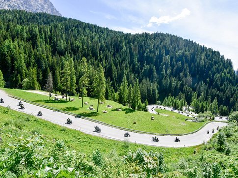 Motorcyclists riding on a winding mountain road through green forests