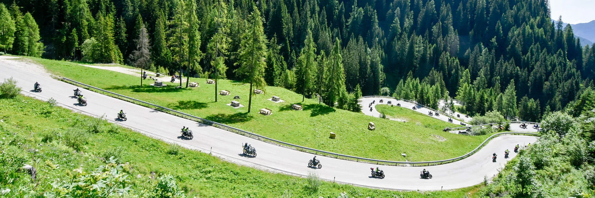 Motorfietsers rijden op een kronkelende bergweg door groene bossen