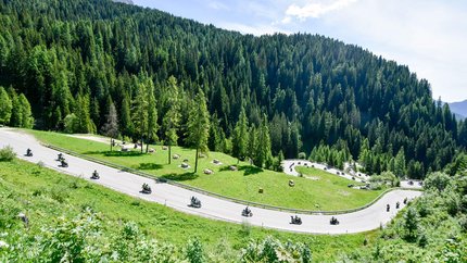 Valsugana – Kaiserjägerstraße – Val di Fiemme © Daniele Rodorigo Motorradfahrer fahren eine kurvige Bergstraße durch grüne Wälder