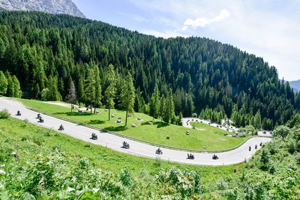 Motorradfahrer fahren eine kurvige Bergstraße durch grüne Wälder