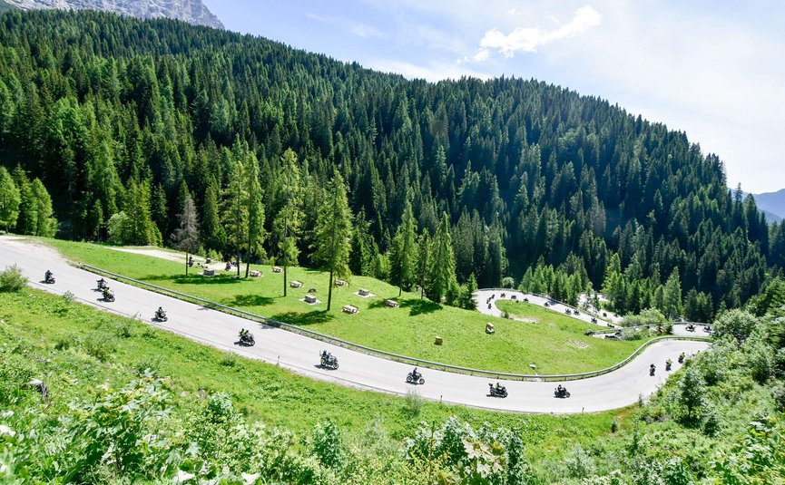 Motorradfahrer fahren eine kurvige Bergstraße durch grüne Wälder