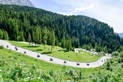 Motorfietsers rijden op een kronkelende bergweg door groene bossen