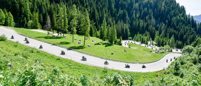 Motorfietsers rijden op een kronkelende bergweg door groene bossen