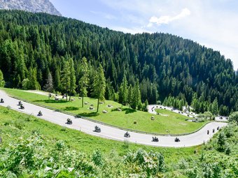 Motorcyclists riding on a winding mountain road through green forests