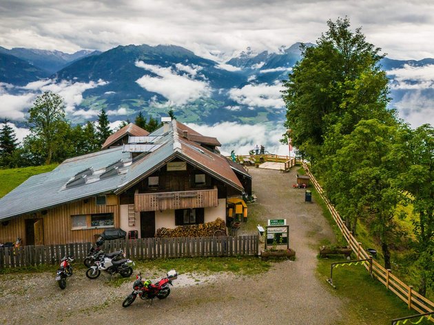 Qualitätsversprechen © Moppetfoto.de Berghütte mit Motorrädern und Nebel über dem Tal bei bewölktem Himmel