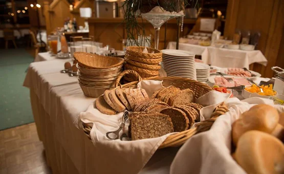 Buffet with various breads and rolls in baskets on a white tablecloth