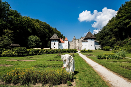 Styria Valleys & Areh Peak Tour A nun tending flowers in the garden of an old monastery on a sunny day