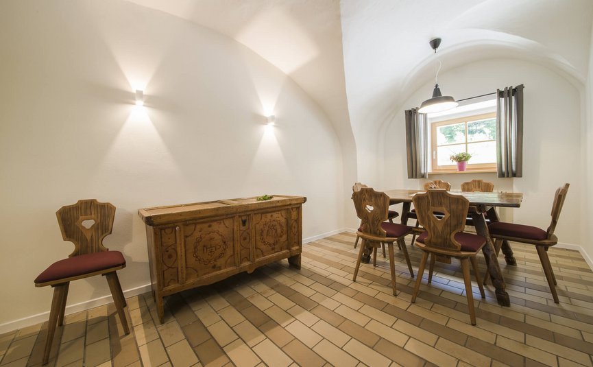 Gezellige eetruimte met houten tafel, stoelen en kast onder gewelfde plafond