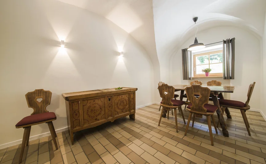 Gezellige eetruimte met houten tafel, stoelen en kast onder gewelfde plafond