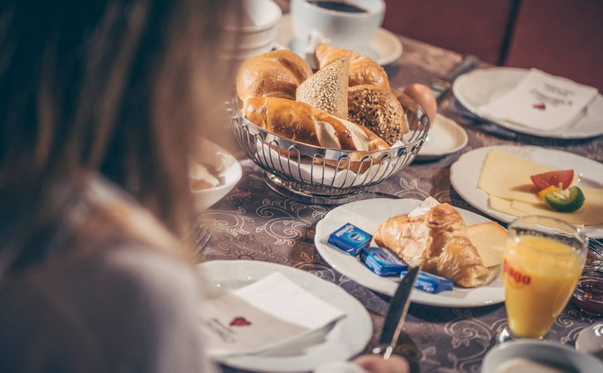 Frühstück mit Brötchen, Croissants, Käse, Orangensaft und Kaffee
