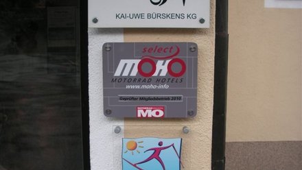 Schilder für MOHO Motorrad Hotels und Langlaufen in Österreich an einer Hauswand