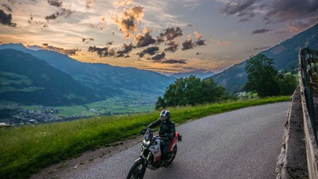 Qualitätsversprechen © Moppetfoto.de Motorradfahrer auf Landstraße bei Sonnenuntergang in bergiger Landschaft