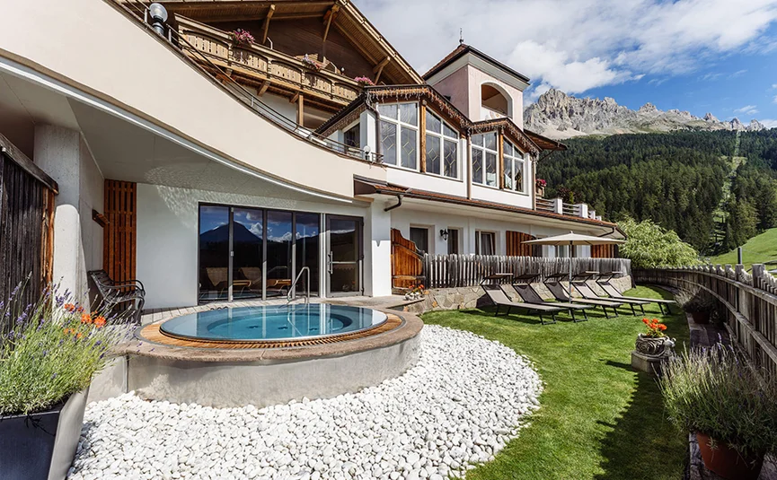 Hotel with hot tub and loungers overlooking mountain scenery