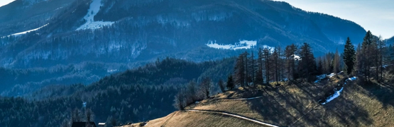 Berglandschap met besneeuwde paden en hutten onder een heldere blauwe lucht