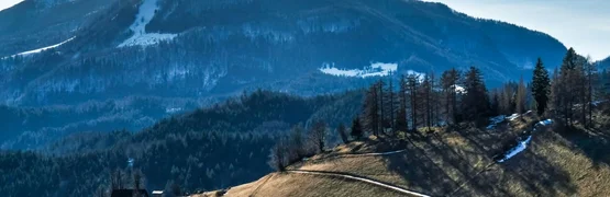 Berge mit verschneiten Pfaden und Hütten in klarer Winterlandschaft
