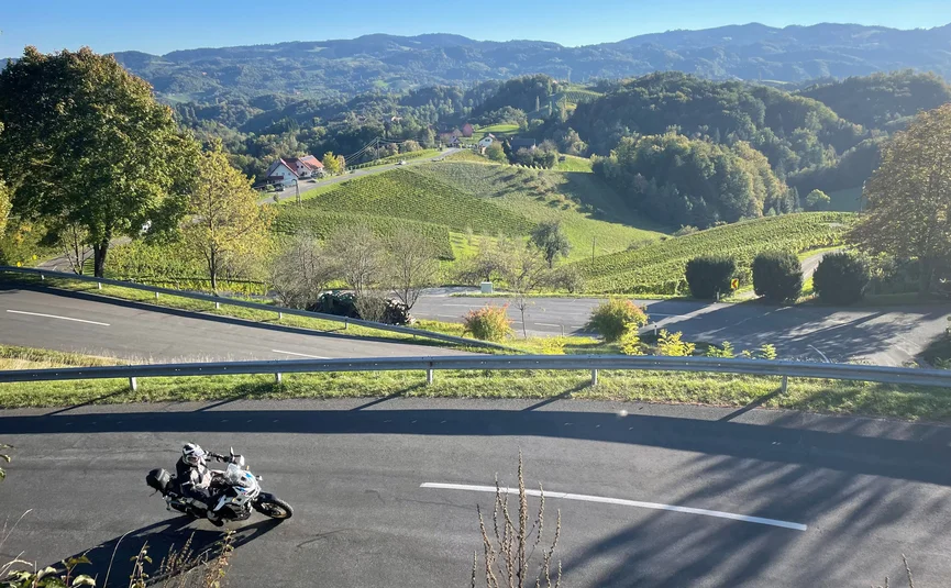 Motorcyclist on winding road in hilly landscape on a sunny day