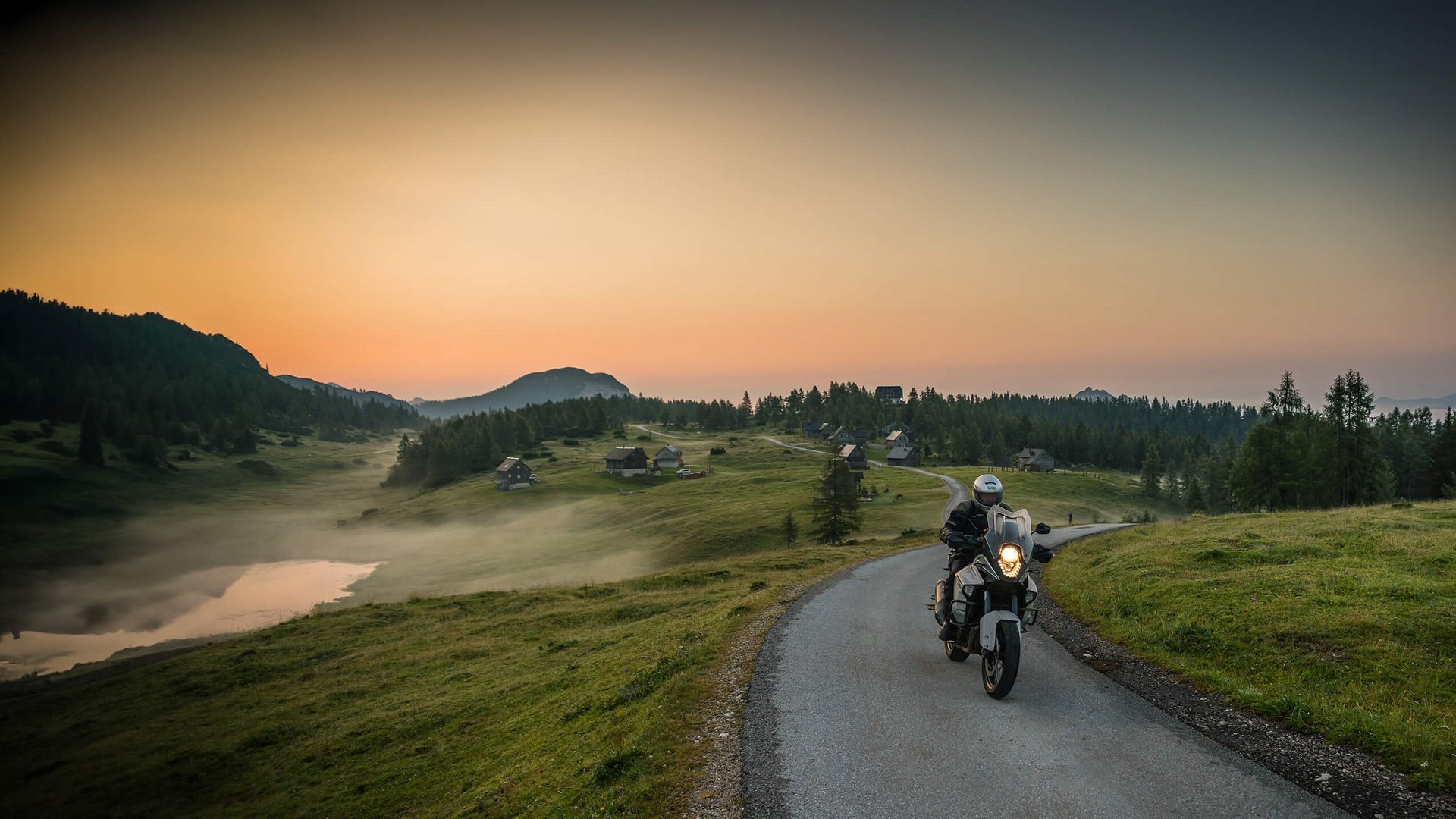 Slowenien © Moppetfoto.de Motorradfahrer fährt auf Landstraße bei Sonnenuntergang mit Hütten und Bergen