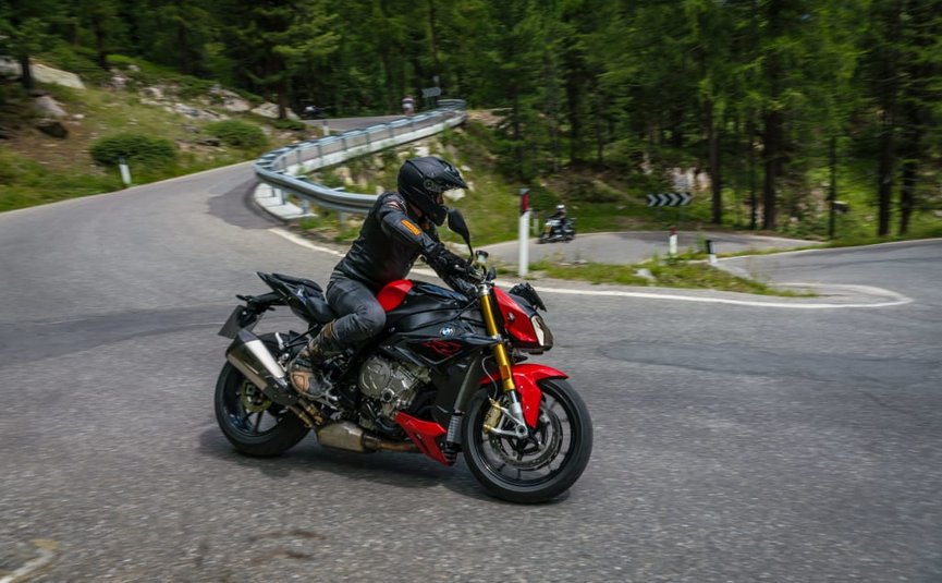 Motorradfahrer auf rotem Motorrad auf kurviger Bergstraße