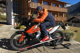 30 Jahre Jubiläums Bike Wochen Person in Skibekleidung sitzt auf Motorrad mit Ski am Vorderrad vor Holzhaus