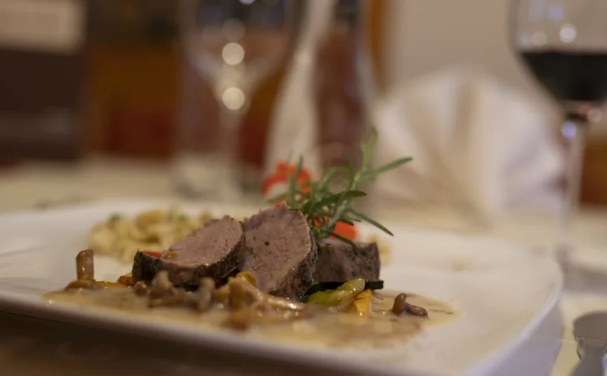 WELLNESS-TAGE am Wochenende Gourmetgericht mit Fleisch, Pilzen und Kräutern auf weißem Teller