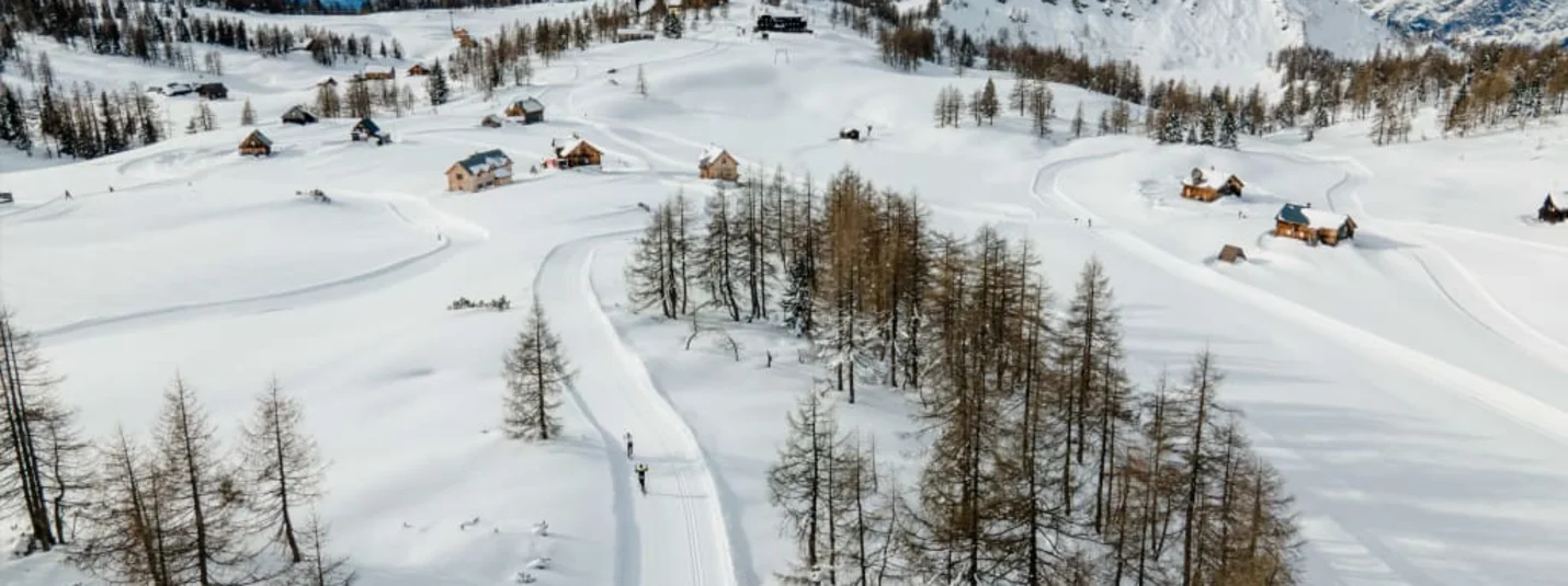 Winterzauber auf der Alm Winterlandschaft mit verschneiten Bergen, Bäumen und kleinen Häusern