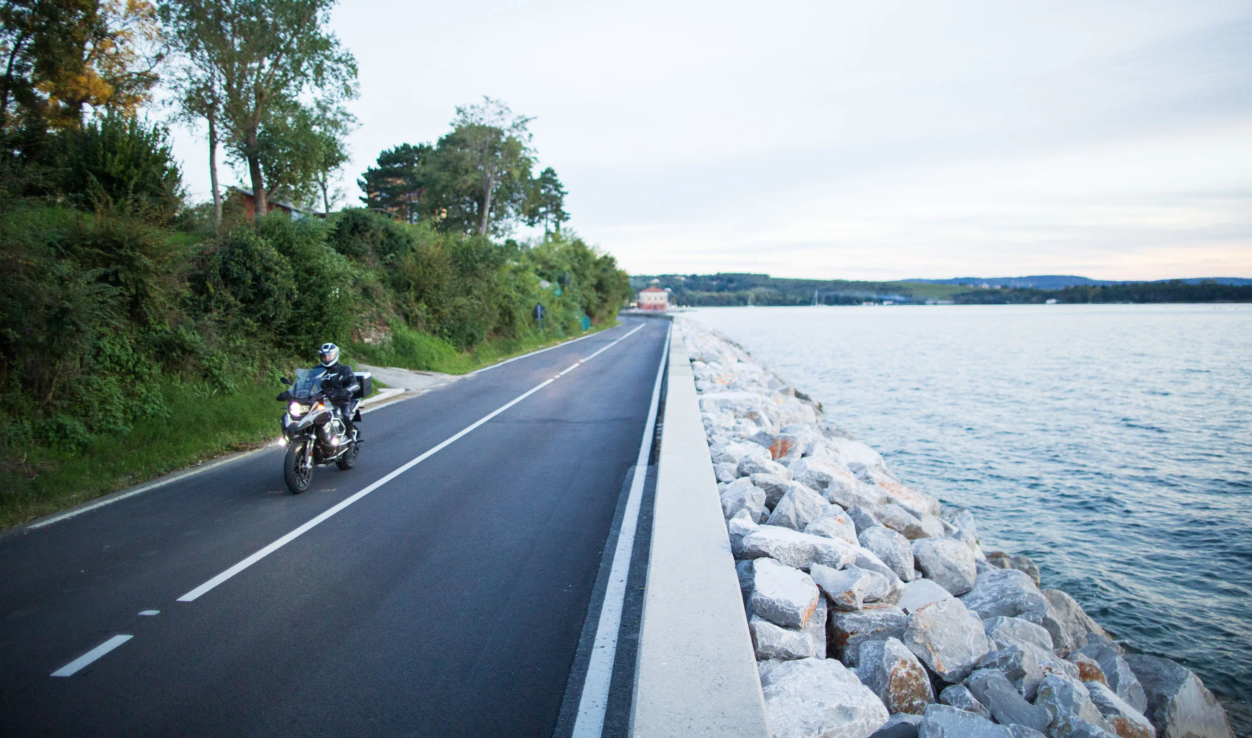 Motorcyclist riding on coastal road next to rocks and water