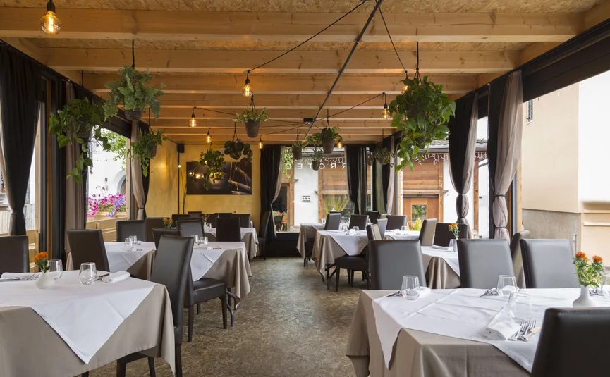 Hotel La Stüa **** © Hotel La Stüa Elegantes Restaurant mit gedeckten Tischen und hängenden Pflanzen an der Decke