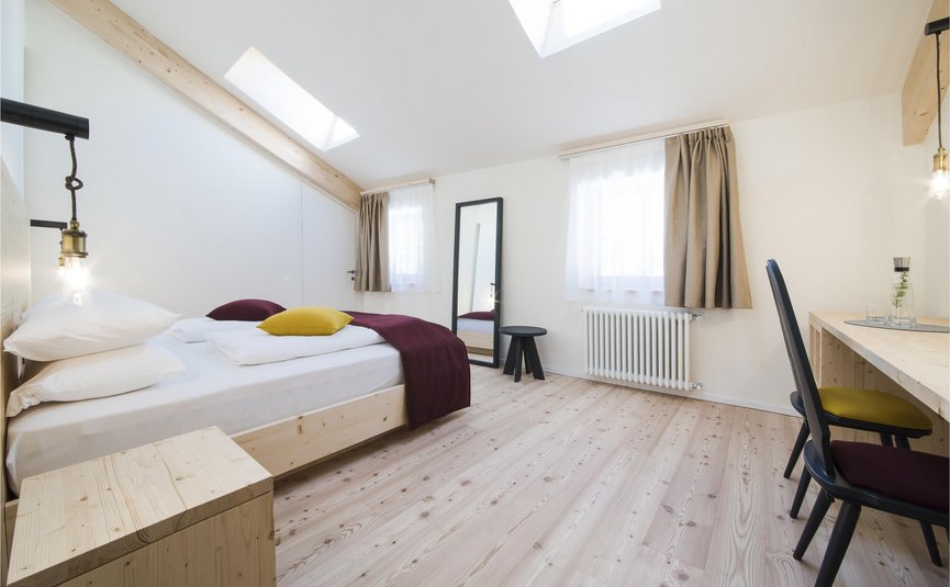 Lichte slaapkamer met dakramen, houten vloer en eenvoudige inrichting