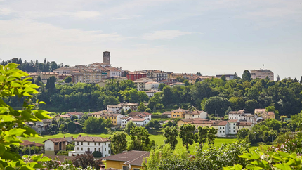 Schinken Runde ( San Daniele) Blick auf ein Dorf mit Häusern, Bäumen und einer Kirchturmspitze bei Tageslicht