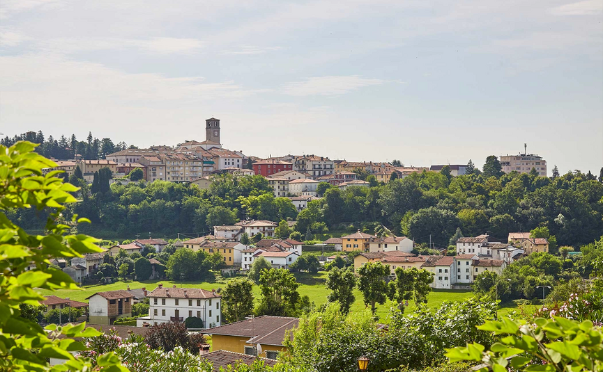 Schinken Runde ( San Daniele) Blick auf ein Dorf mit Häusern, Bäumen und einer Kirchturmspitze bei Tageslicht