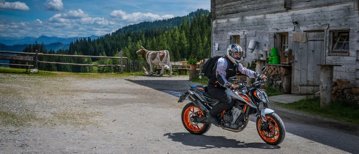 Motorcyclist in front of wooden house in mountain landscape under blue sky