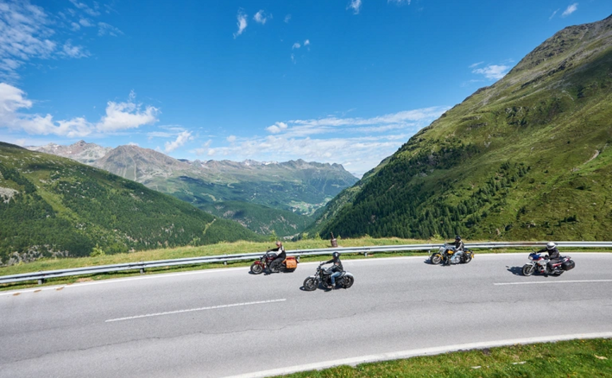 Südtirol Runde Vier Motorradfahrer fahren auf kurviger Bergstraße bei klarem Himmel