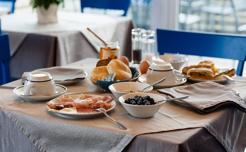 Frühstückstisch mit Brötchen, Aufschnitt, Blaubeeren und Kaffee