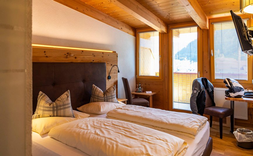 Gezellige slaapkamer met twee bedden, houten muren en balkon met bergzicht