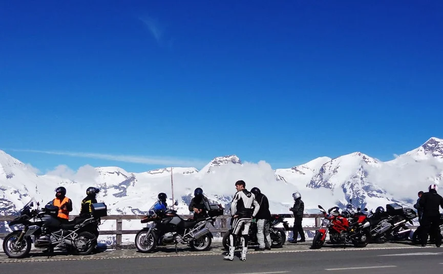 3 Nächte Kurvenkönig Special ab € 344,- pro Person Motorrijders met motoren op bergweg bij besneeuwde toppen